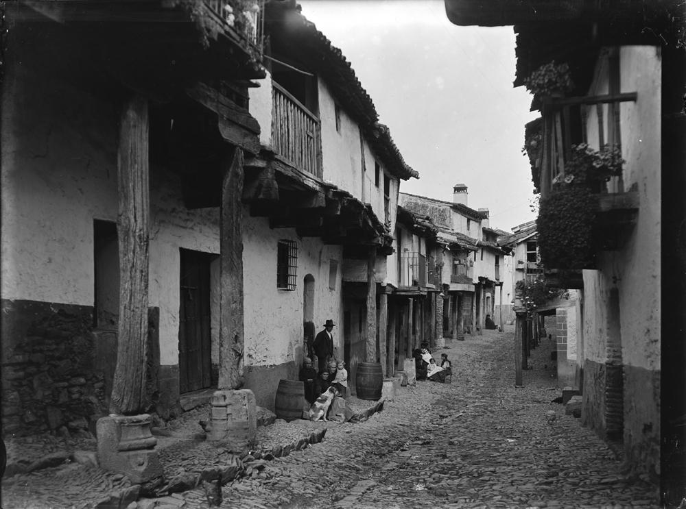 Calle empedrada con casas típicas y personas sentadas