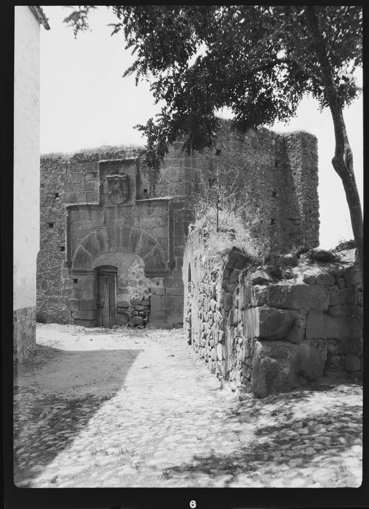 Calle empedrada con puerta de madera bajo arco de medio punto