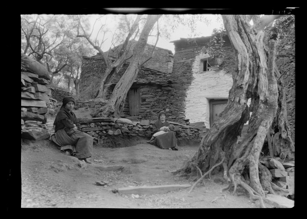 Casas de pizarra y mampostería, olivos y mujeres sentadas fuera