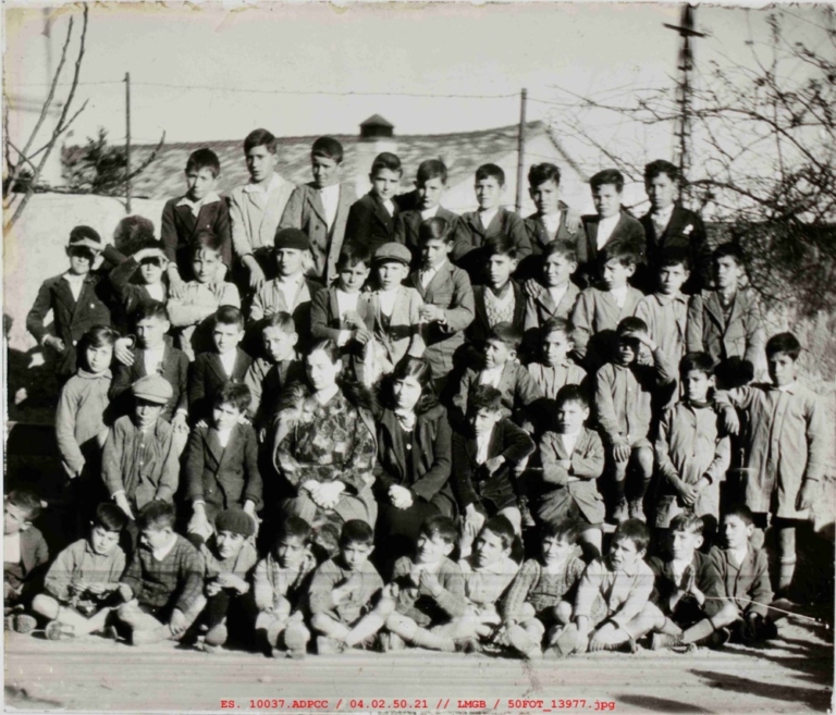 Fotografía de grupo de niños de varias edades delante de un muro
