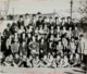 Fotografía de grupo de niños de varias edades delante de un muro, 1930