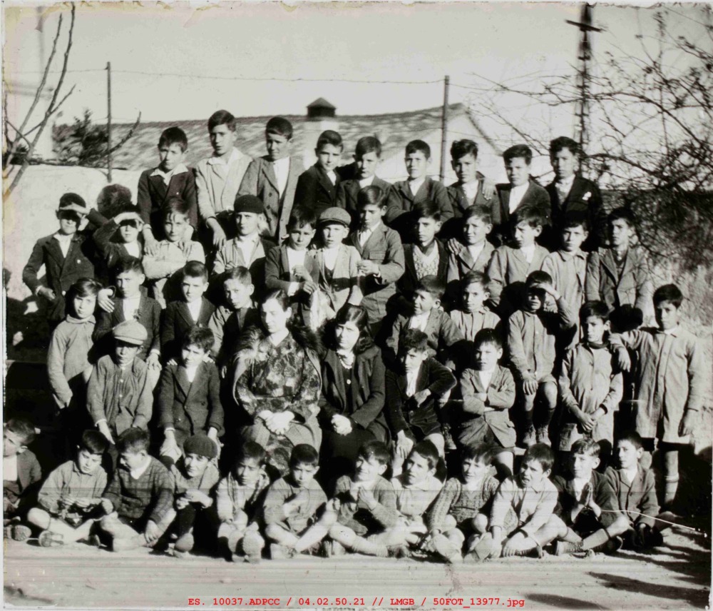 Fotografía de grupo de niños de varias edades delante de un muro