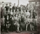 Fotografía de grupo de niños de varias edades delante de un muro, 1930