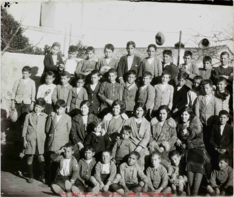 Fotografía de grupo de niños de varias edades delante de un muro