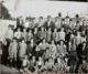 Fotografía de grupo de niños de varias edades delante de un muro, 1930