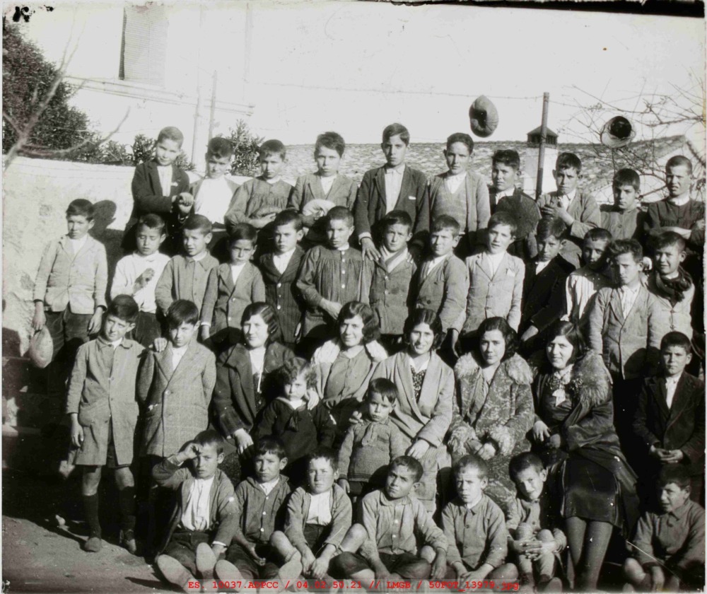 Fotografía de grupo de niños de varias edades delante de un muro