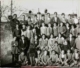 Fotografía de grupo de niños de varias edades delante de un muro, 1930