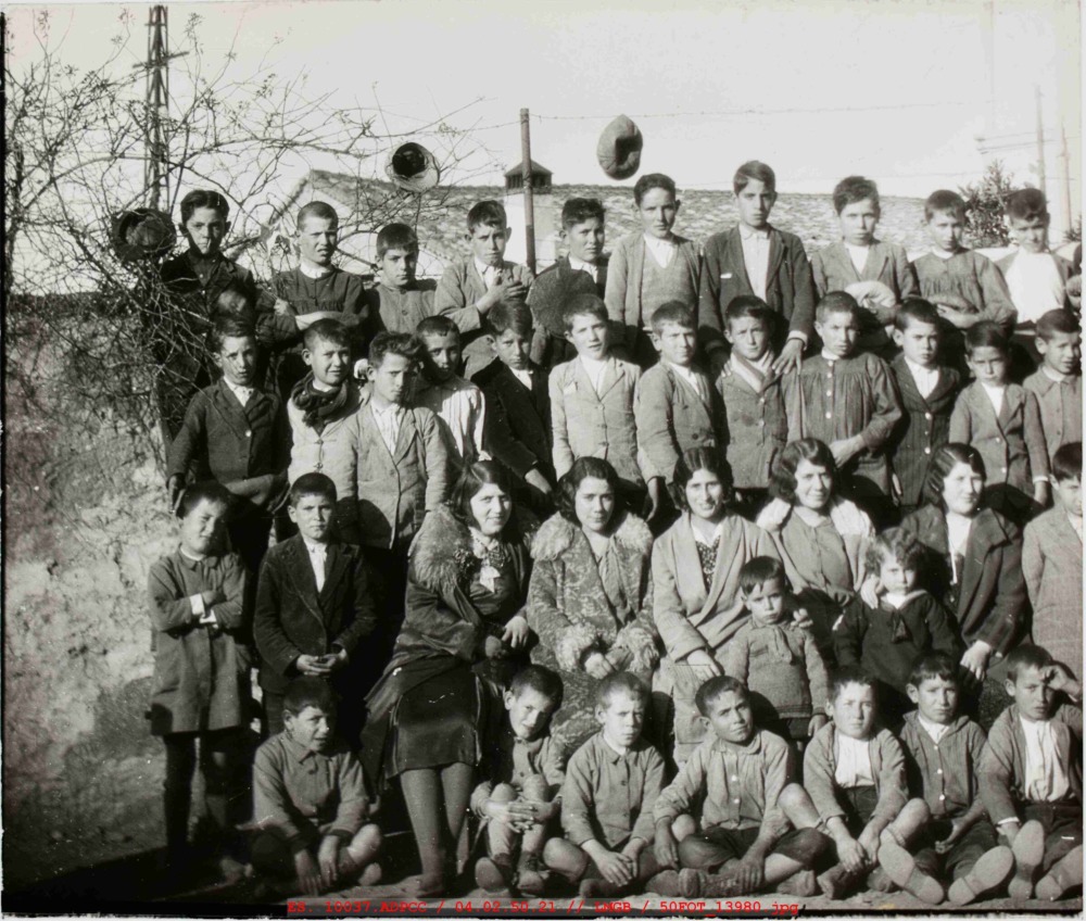 Fotografía de grupo de niños de varias edades delante de un muro
