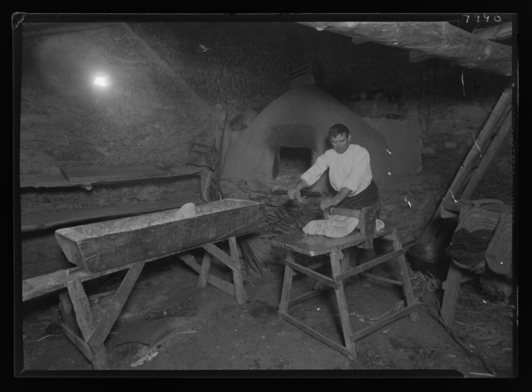 Hombre amasando pan: horno al fondo
