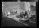 Hombre cargando sacos en una mula; ropa a la venta en el muro de una iglesia · Ruth Matilda Anderson, 1928