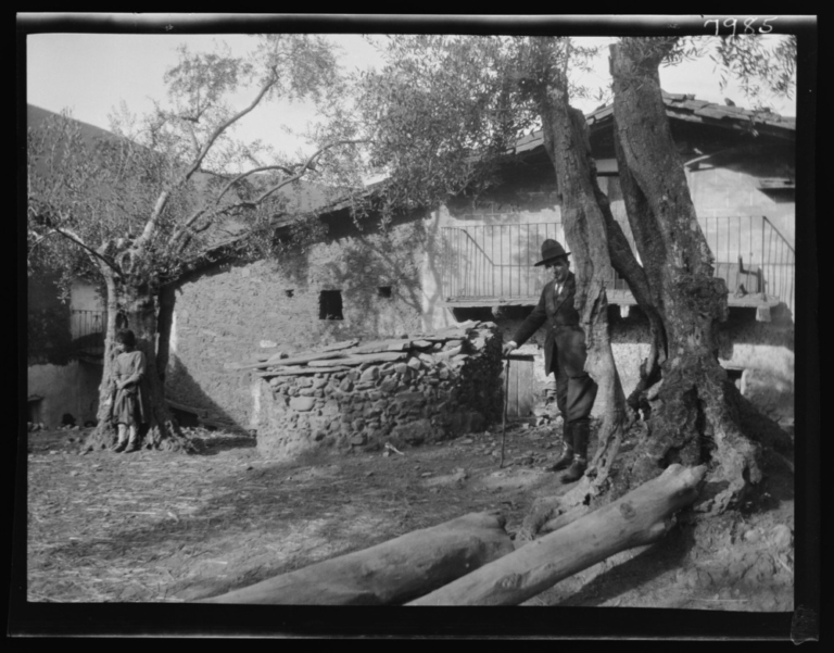Hombre posando junto a una casa y unos olivos
