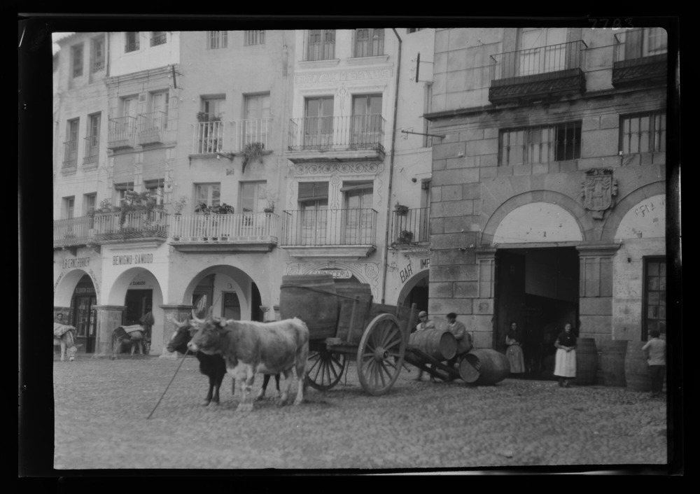 Hombres cargando barriles de vino en un carro de dos ruedas