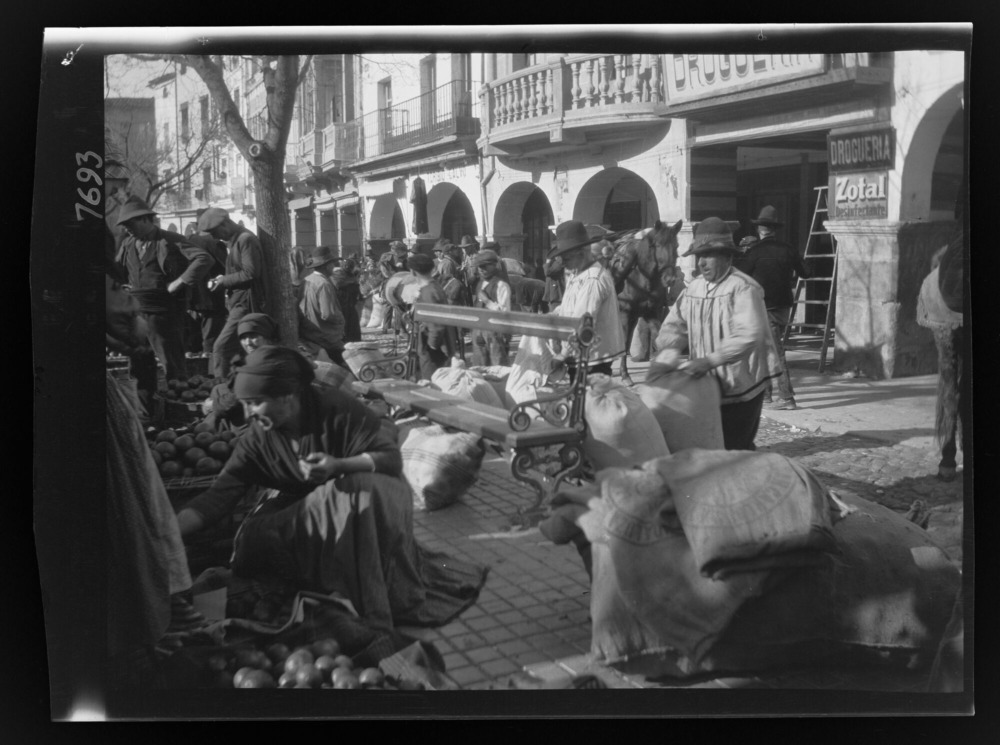 Mercado en la plaza: dos hombres colocando sacos de grano