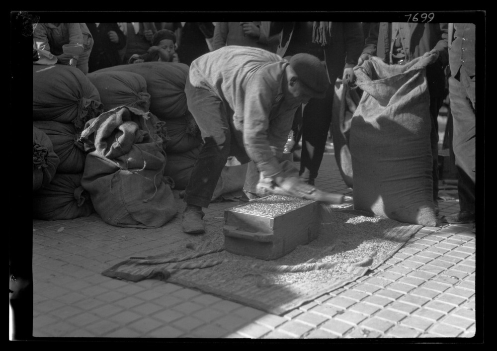 Mercado en la plaza: hombre midiendo cebada