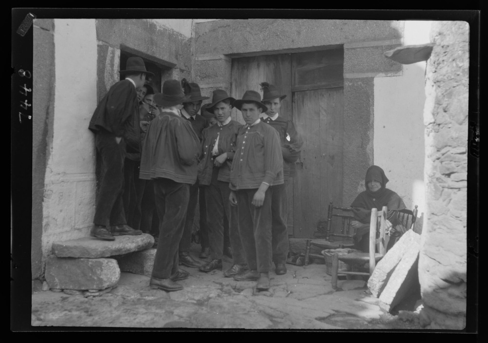 Mozos esperando fuera de una casa mientras sus amigos bailan