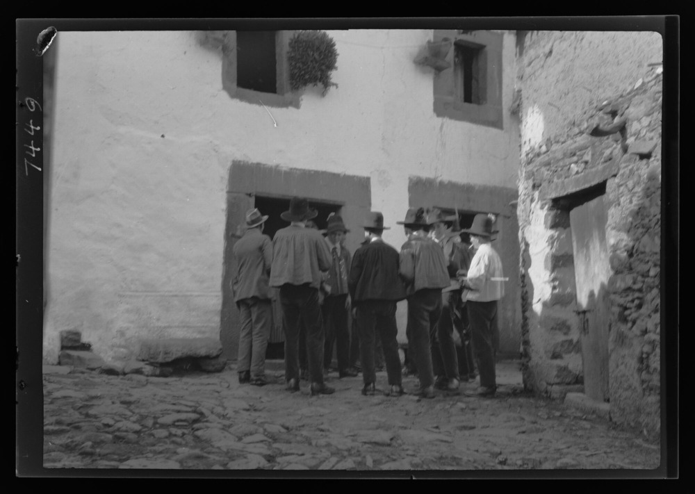 Mozos esperando fuera de una casa mientras sus amigos bailan