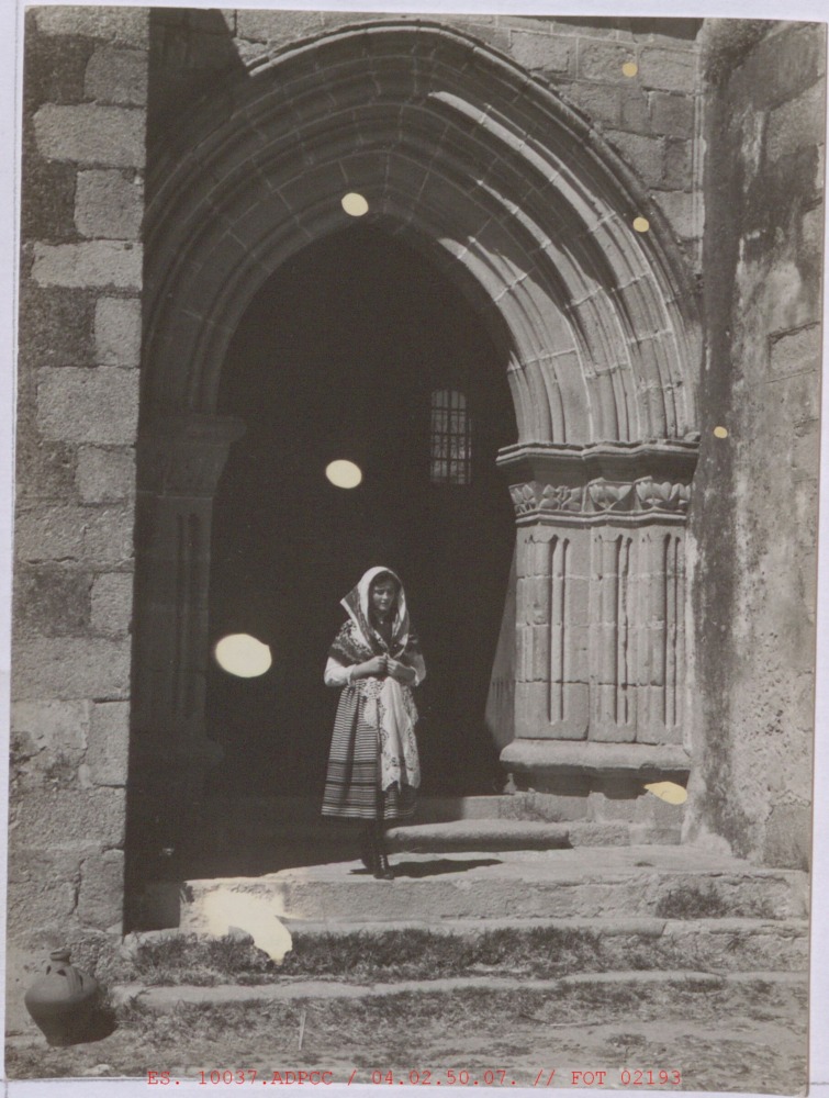 Mujer con trajes típico junto a la puerta de la iglesia
