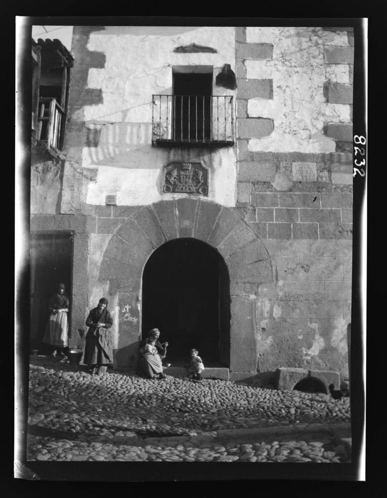 Mujer dando de comer a un niño en el umbral de una puerta en arco