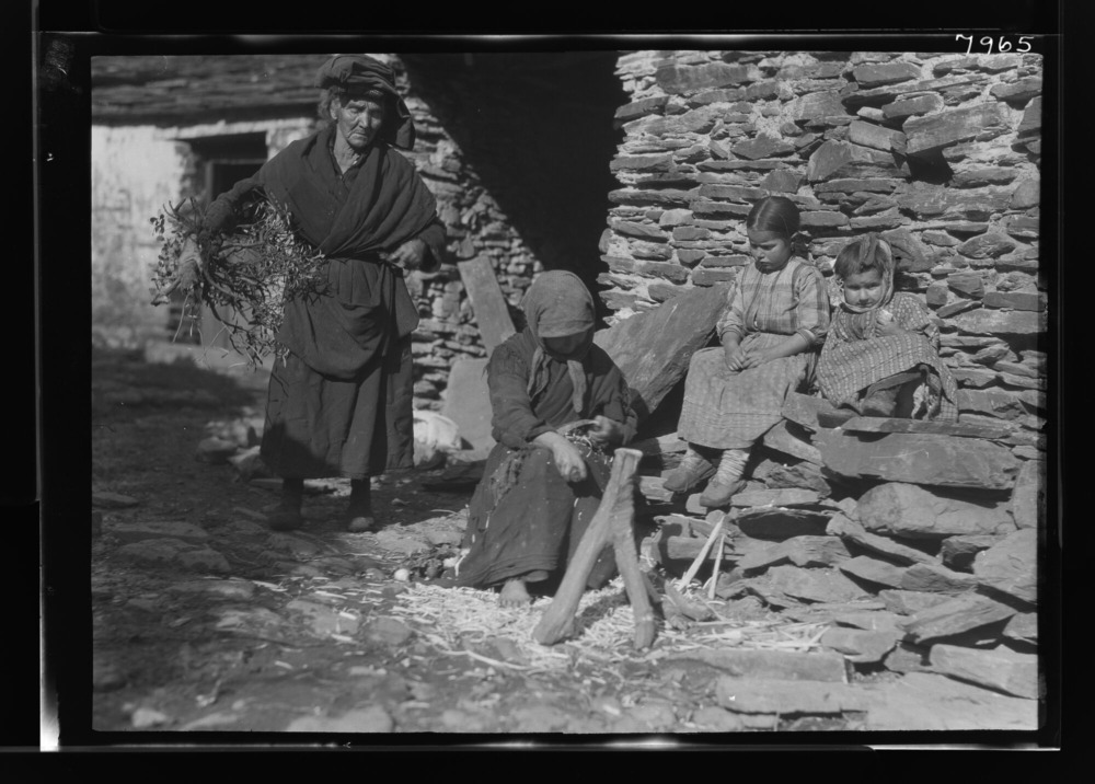 Mujer haciendo palos para una colmena; otra lleva ramas de olivo