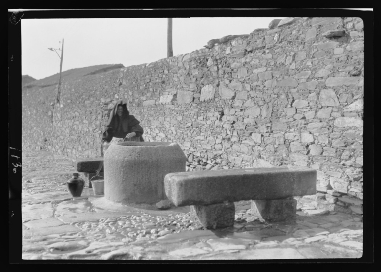 Mujer llenando cántaros de agua en una fuente
