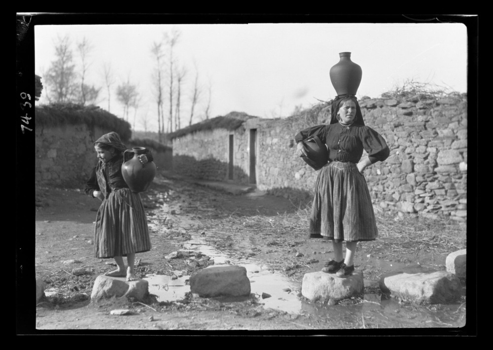 Mujer y niña volviendo de la fuente con los cántaros llenos