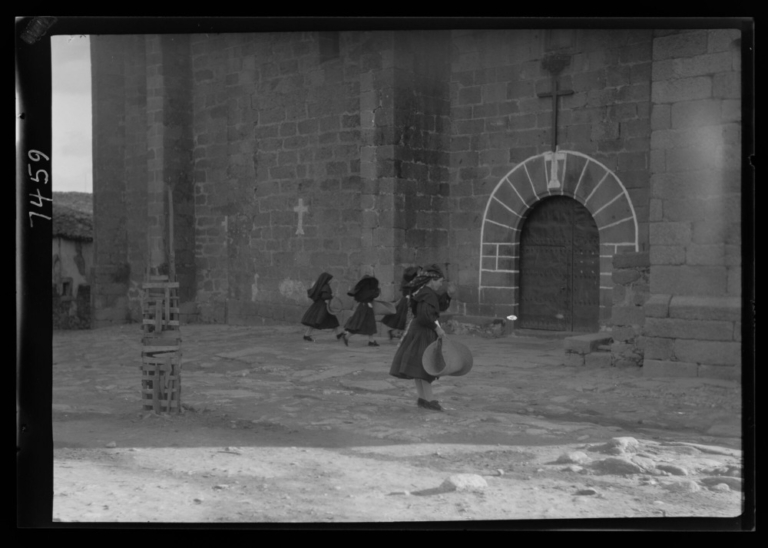 Mujeres entrando a misa con esterillas de esparto para arrodillarse