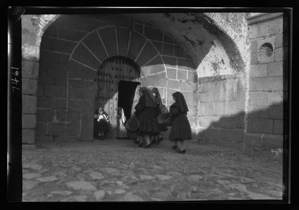 Mujeres entrando a misa con esterillas de esparto para arrodillarse