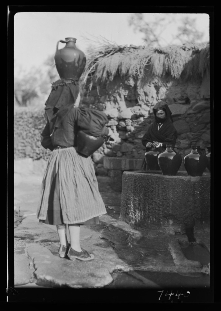 Mujeres llenando cántaros de agua en una fuente