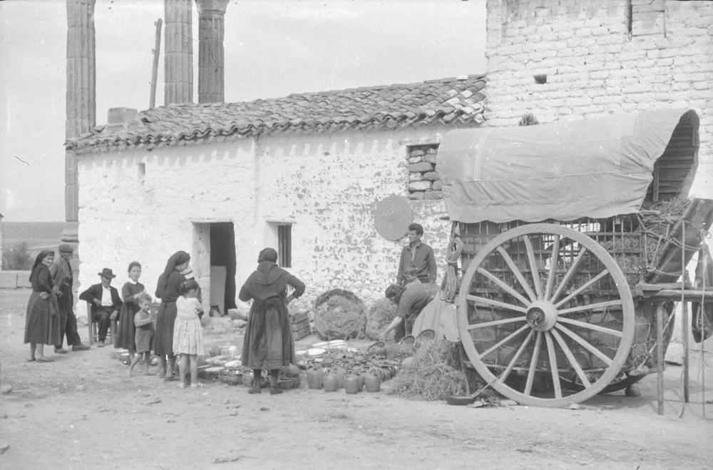 Mujeres y niños en torno a una comerciante de botijos y platos
