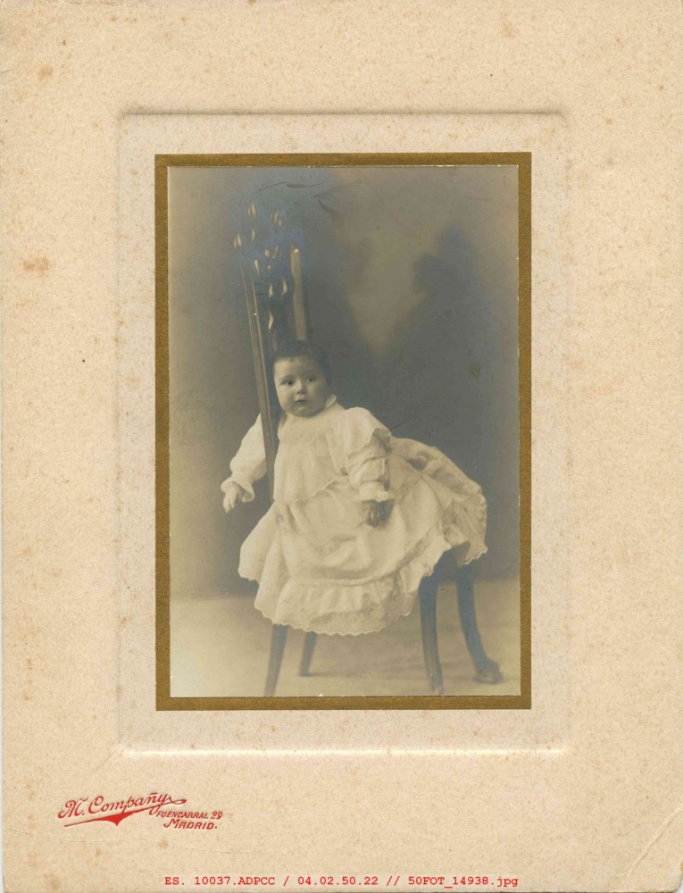 Niña vestida de blanco en una silla