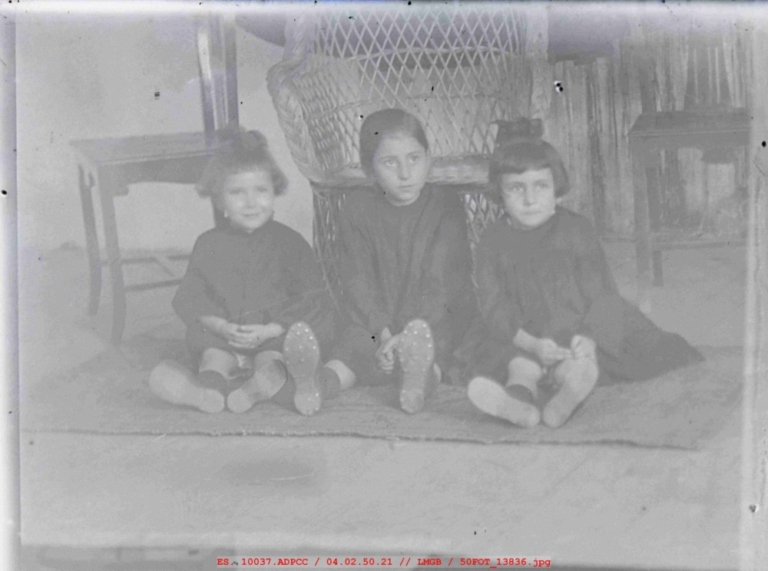 Tres niñas sentadas vestidas de luto