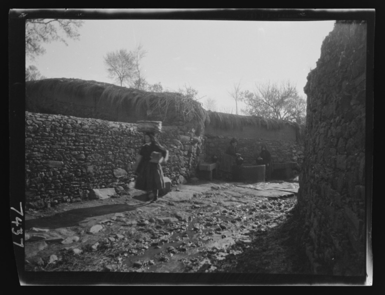 Vista lejana de mujeres llenando cántaros de agua en una fuente