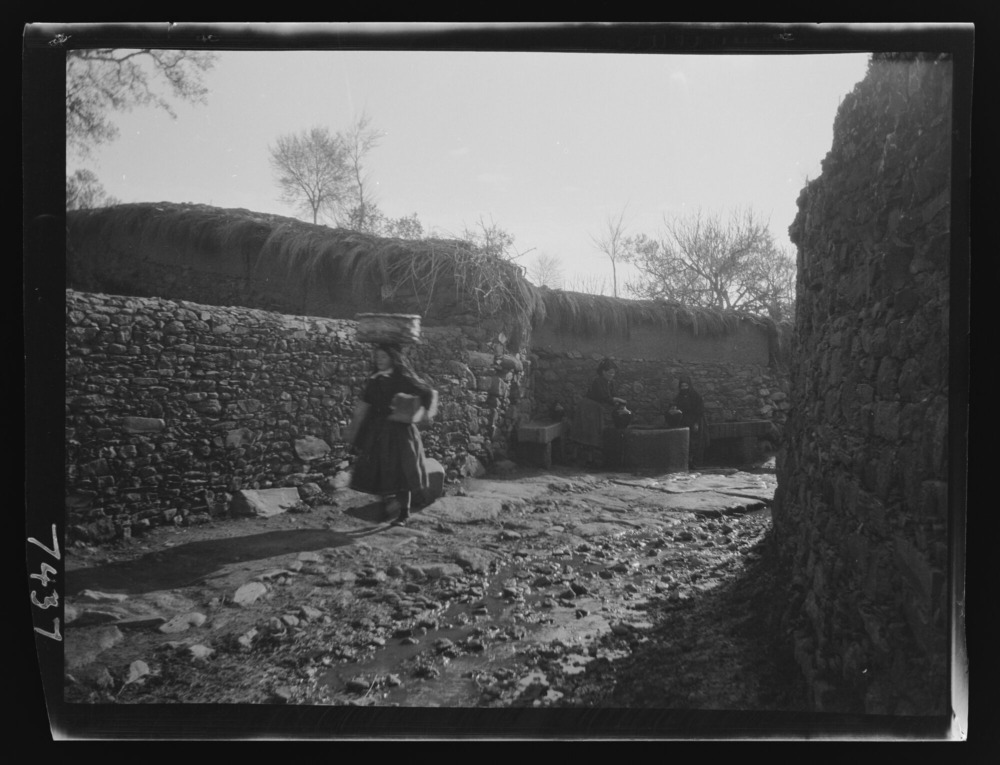 Vista lejana de mujeres llenando cántaros de agua en una fuente